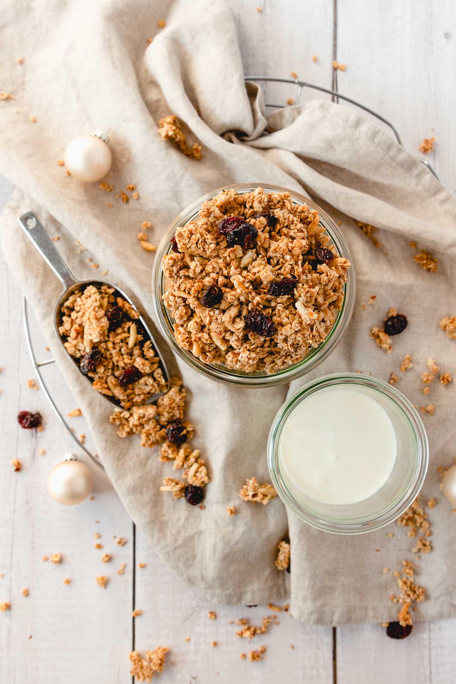 christmas spiced granola with cranberries in weck jar with yoghurt on beige linen napkin with props.