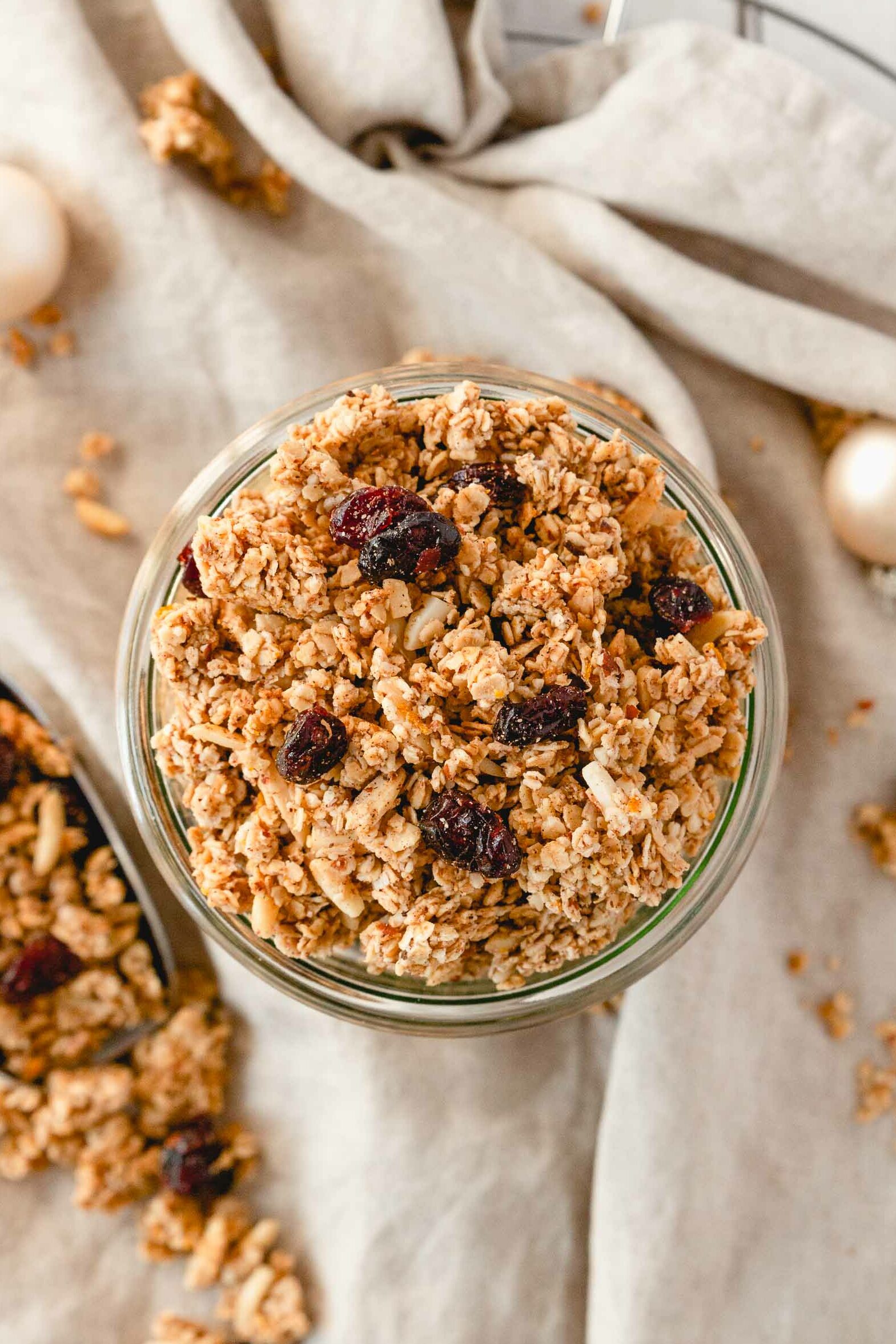 christmas spiced granola with cranberries in weck jar on beige linen napkin with props.