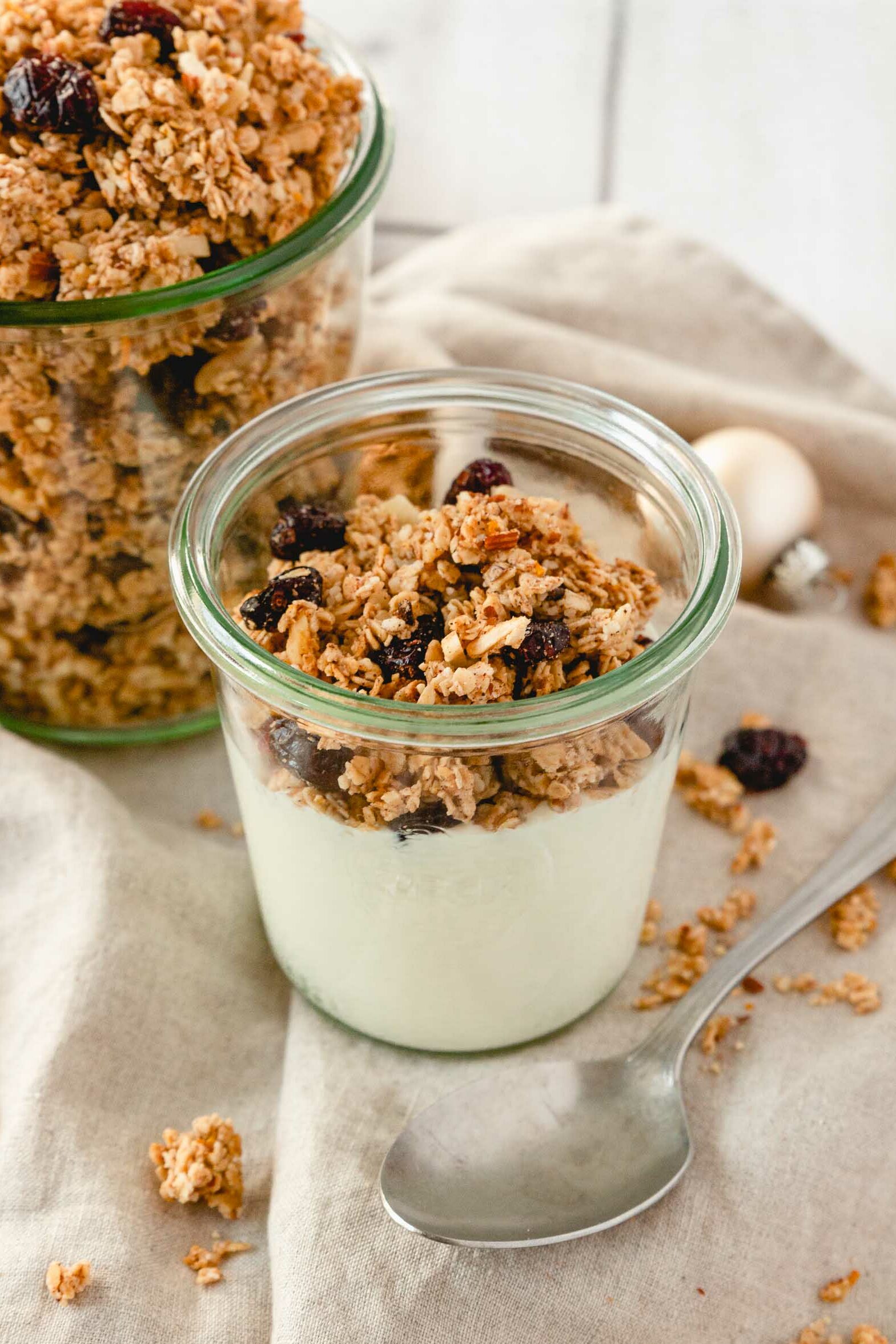 gingerbread granola with yoghurt in weck jar on beige linen napkin with vintage spoon.