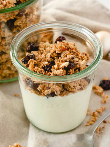 gingerbread granola with yoghurt in weck jar on beige linen napkin with vintage spoon.