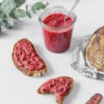 raspberry chia jam spread on dark bread with vintage knife laying next to it and weck jar wir jam