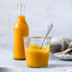 spicy mango sauce in weck jar and bottle standing on grey blue background with vintage spoon