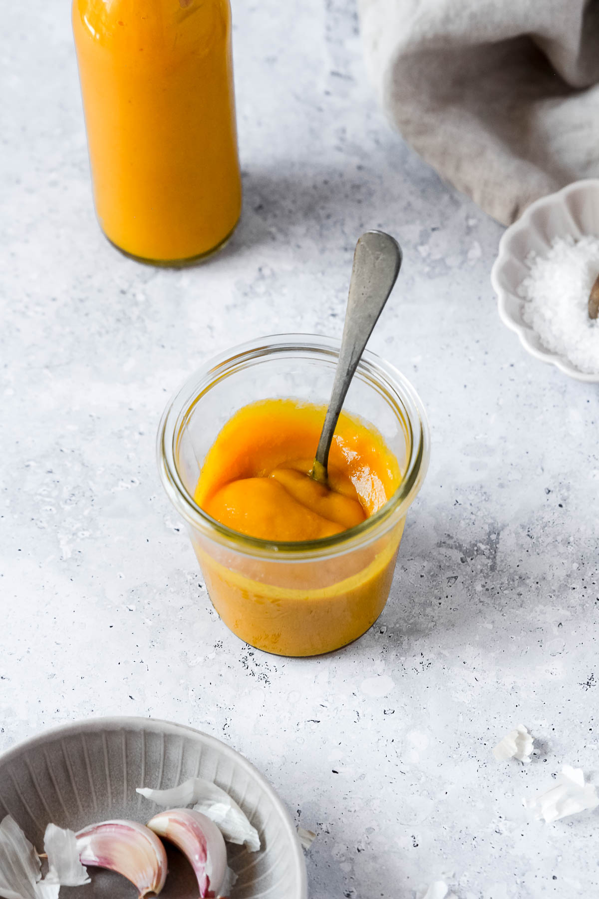 spicy mango sauce in weck jar and bottle standing on grey blue background with vintage spoon