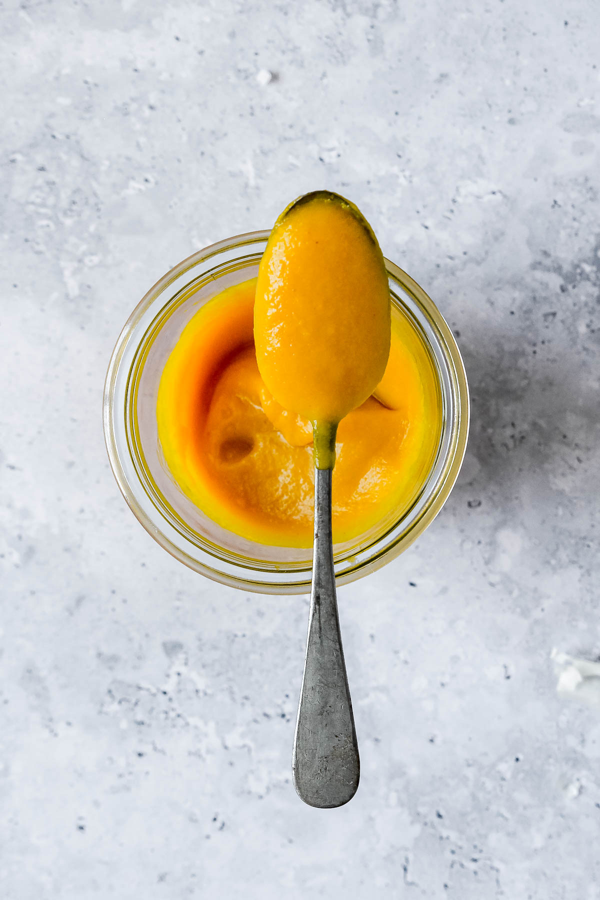 vibrant and spicy mango sauce in weck jar with vintage spoon on grey blue background