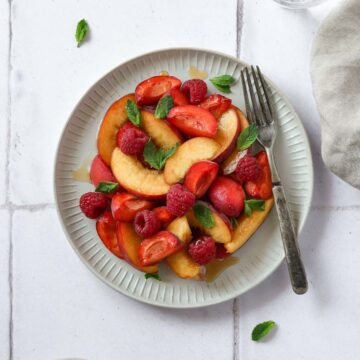 different stone fruits on grey plate with vintage fork