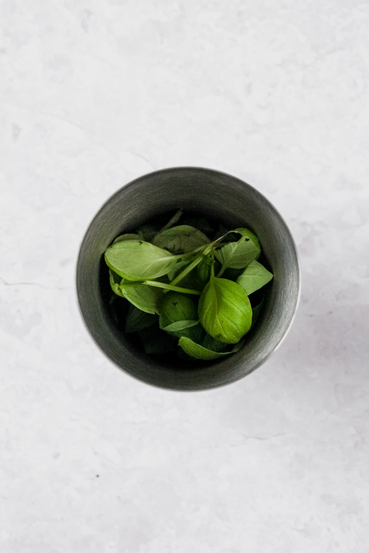 ingredients for gin basil smash in cocktail shaker on grey marble background.