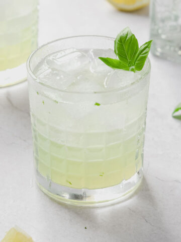 gin basil smash with basil garnish on grey marble background.