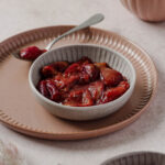 plum compote in grey bowl with vintage spoon on dusty rose plate