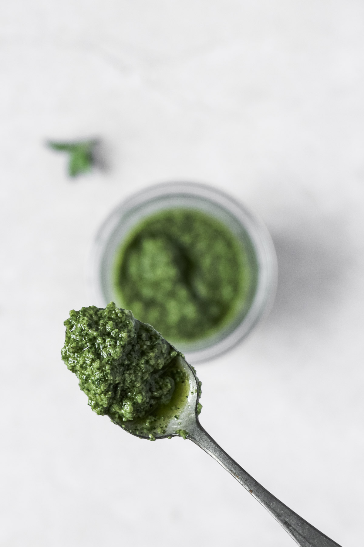 thai basil pesto on vintage spoon with pesto in weck jar in the background.