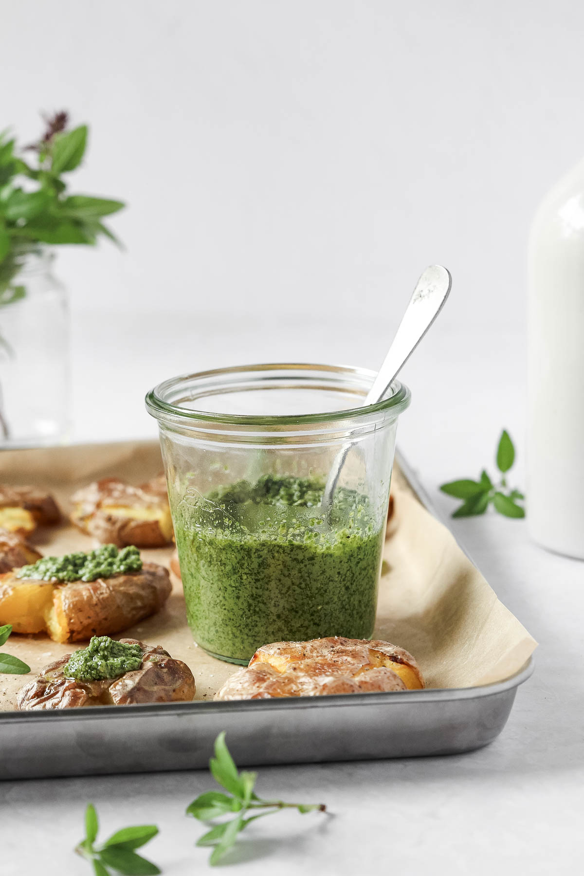 thai basil pesto in weck jar on baking sheet with smashed potatoes.