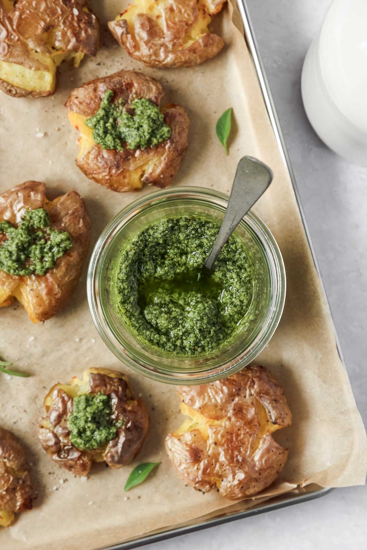 thai basil pesto in weck jar on baking sheet with smashed potatoes.