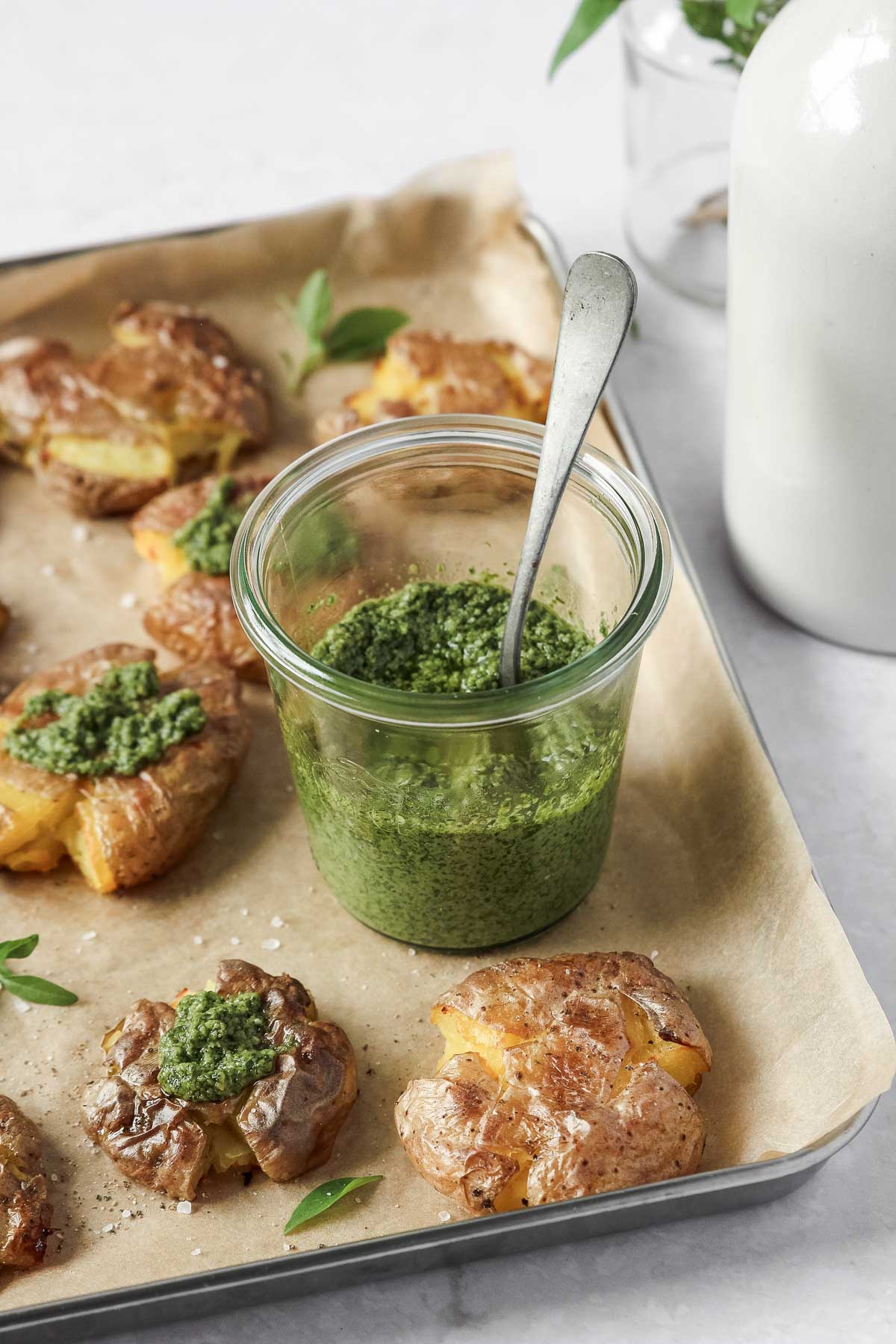 thai basil pesto in weck jar on baking sheet with smashed potatoes.