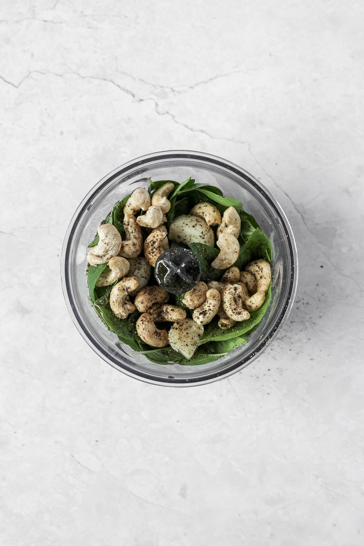 ingredients for thai basil pesto in food processor on marble background.