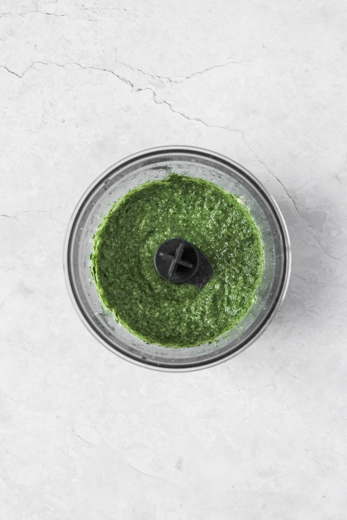 thai basil pesto in food processor on marble background.