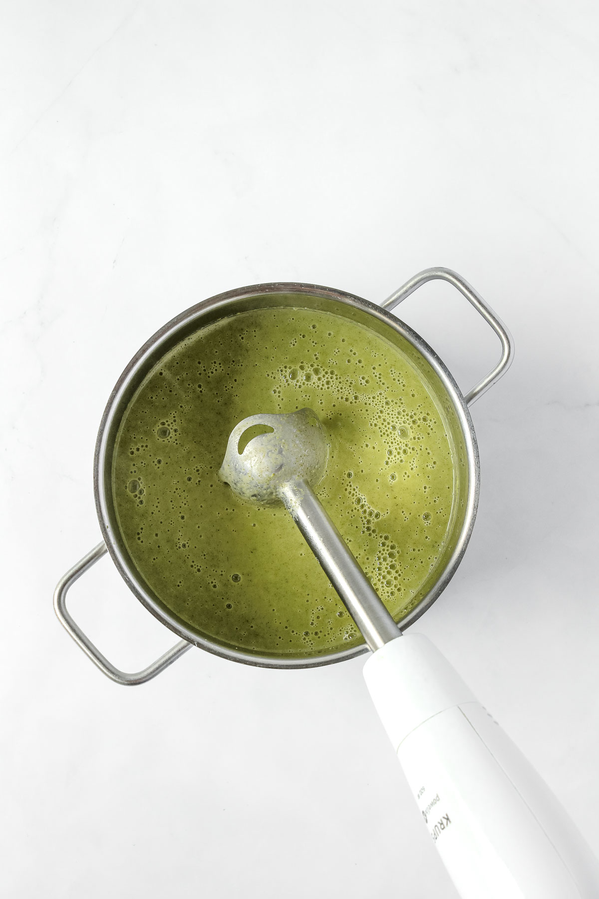 blending broccoli soup in pot with an immersion blender.