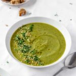 vegan broccoli soup with vintage spoon on white background.