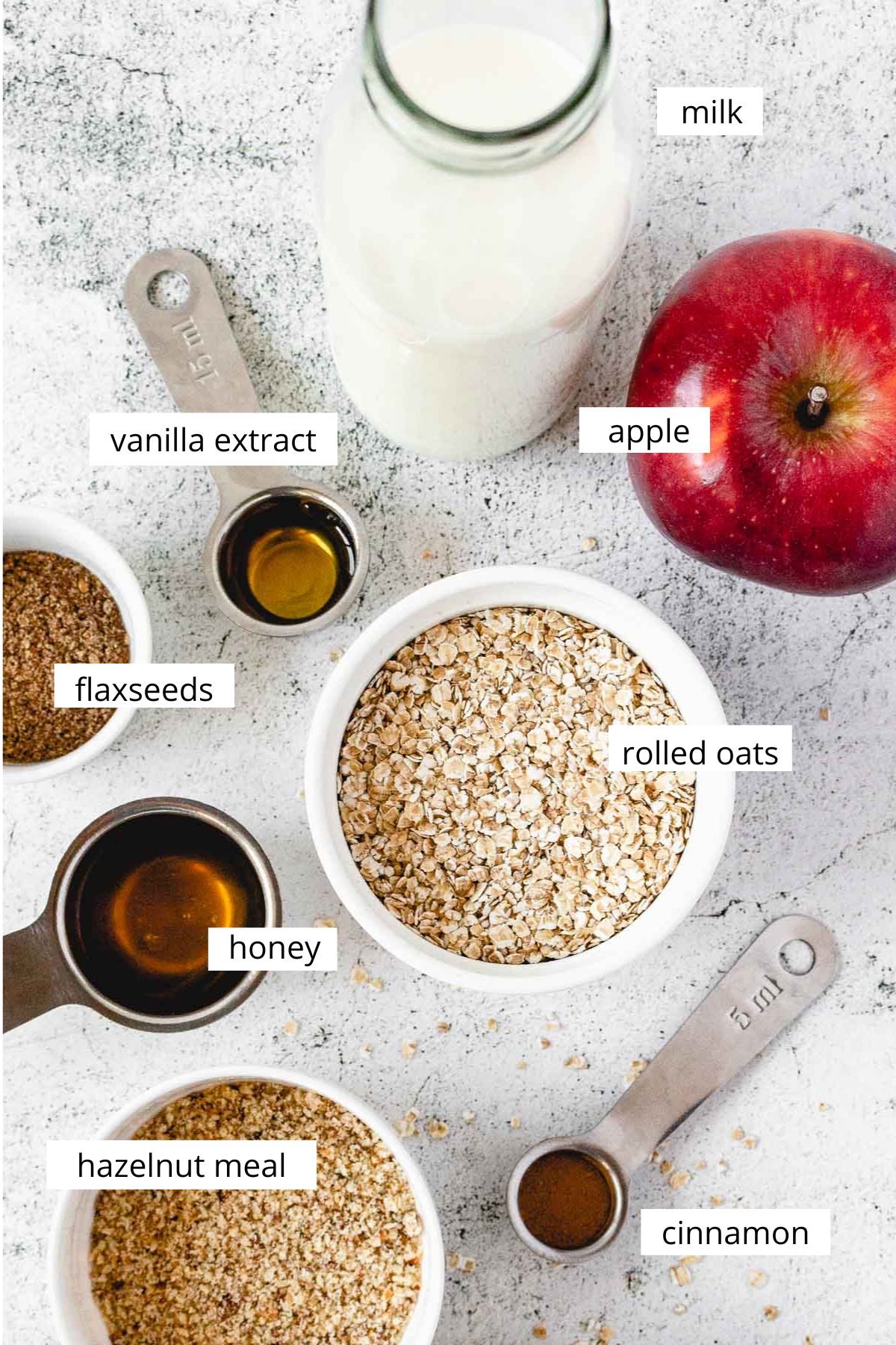 ingredients for apple cinnamon oatmeal on light grey background.