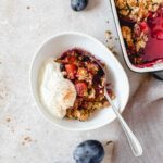 apple and plum crumble in bowl with yoghurt with vintage spoon