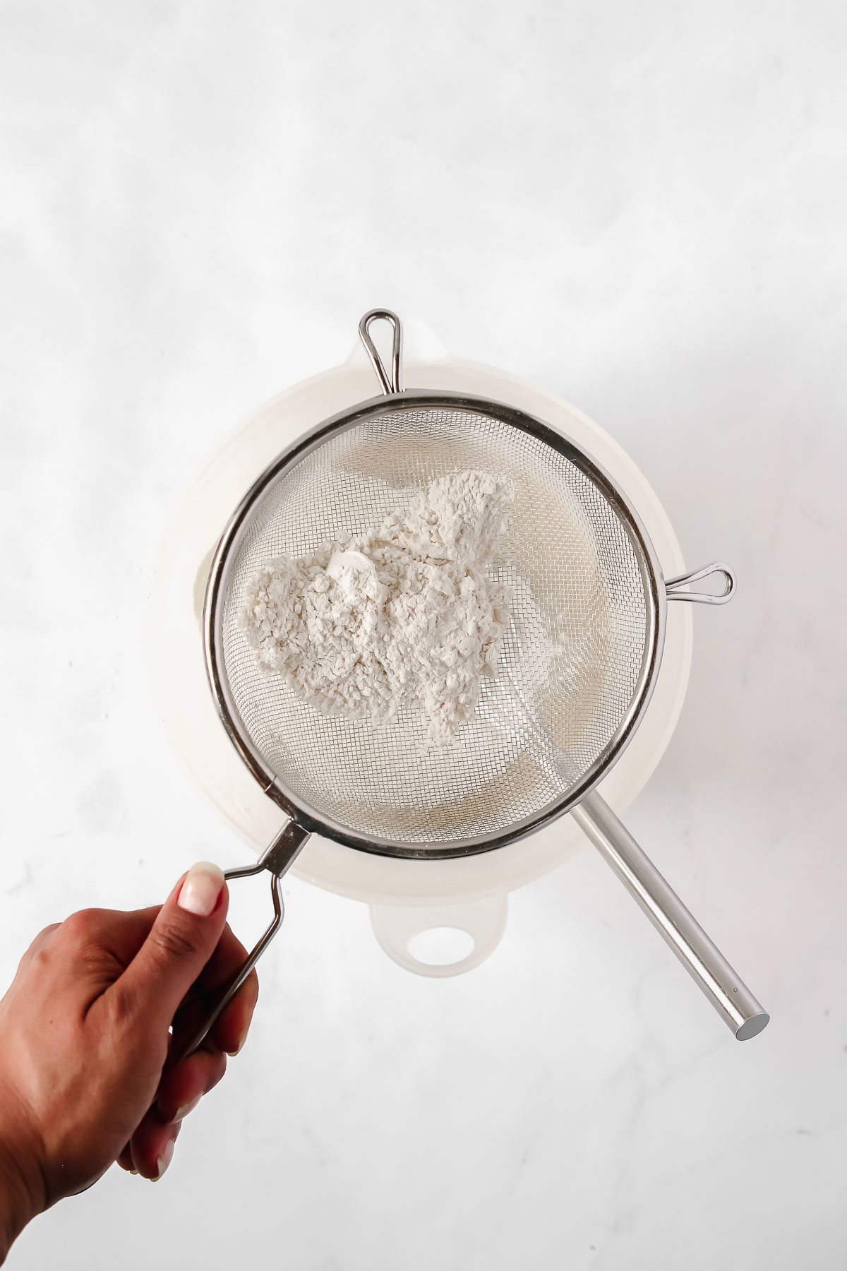 sifting flour into egg and sugar mixture for a grape cake.