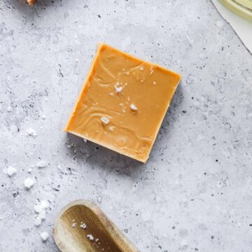 peanut butter fudge sprinkled with flaky sea salt on blue background with props.