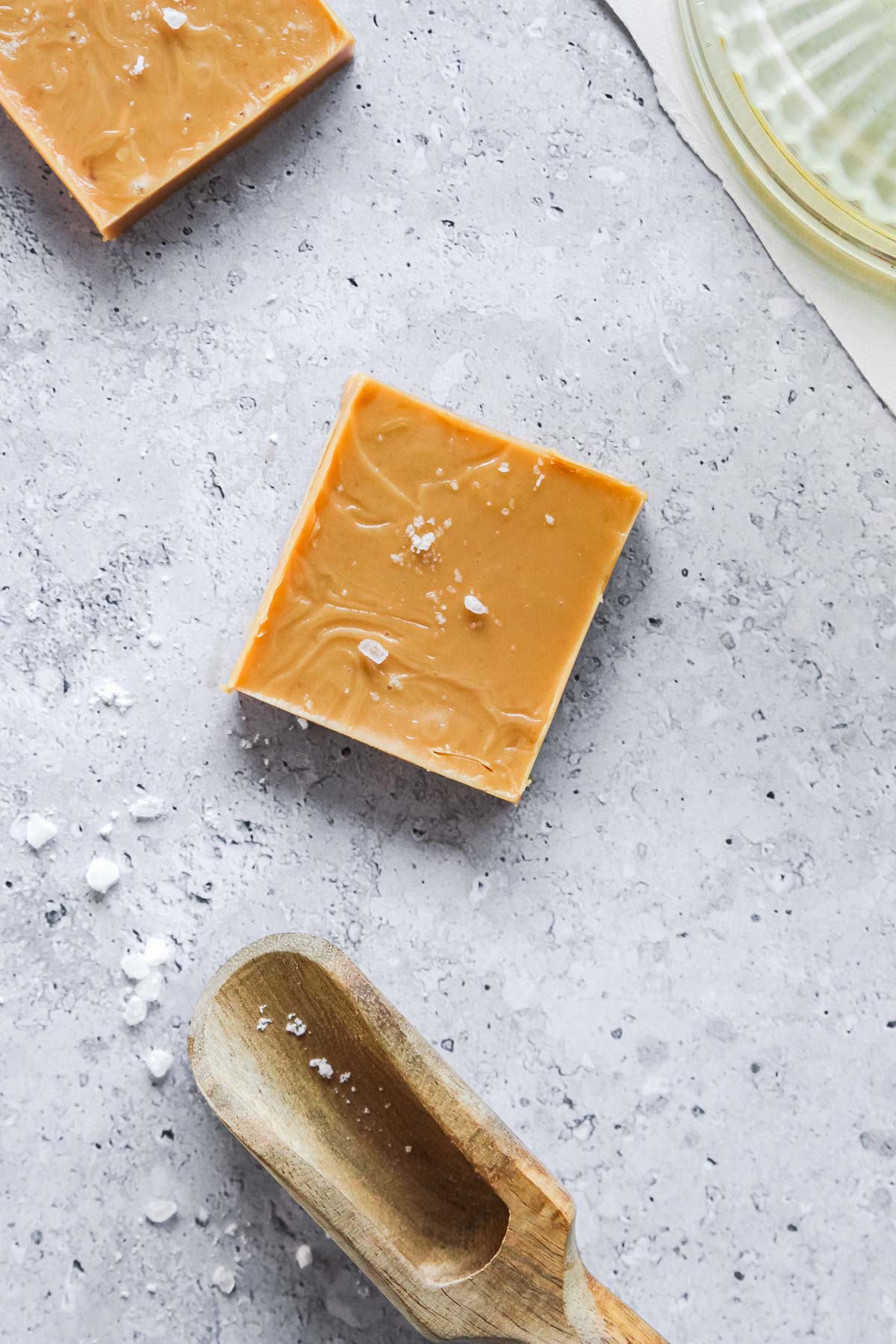 peanut butter fudge sprinkled with flaky sea salt on blue background with props.