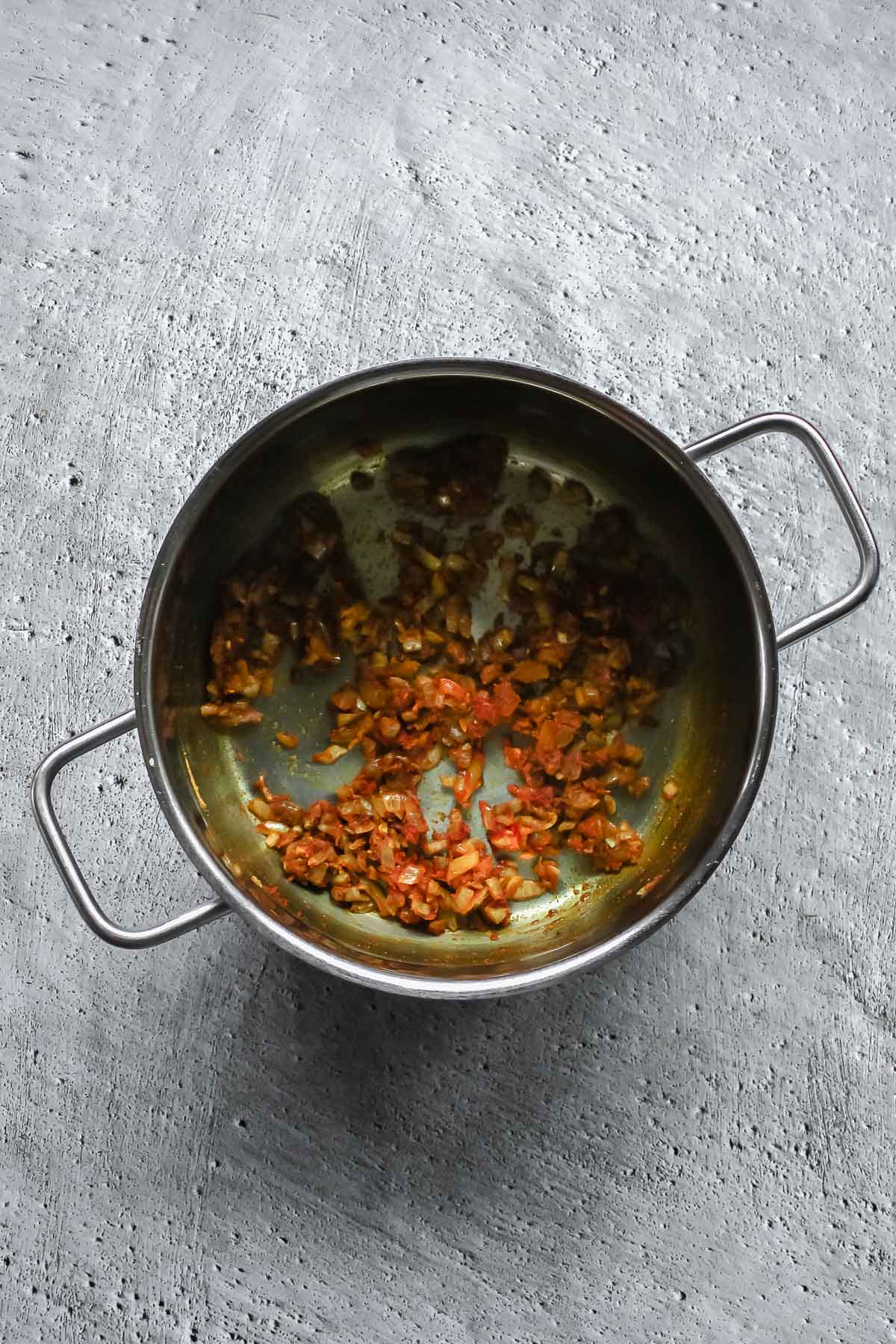 spices for curry and oil roasting in pot on grey background.