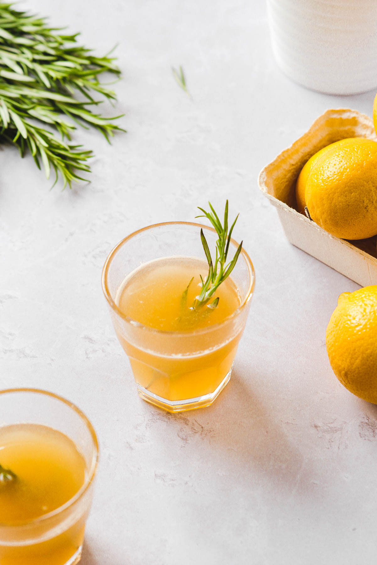 lemon drops with honey and rosemary garnish on light grey background with props.