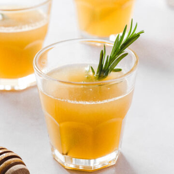 lemon drops with honey and rosemary garnish on light grey background with props.
