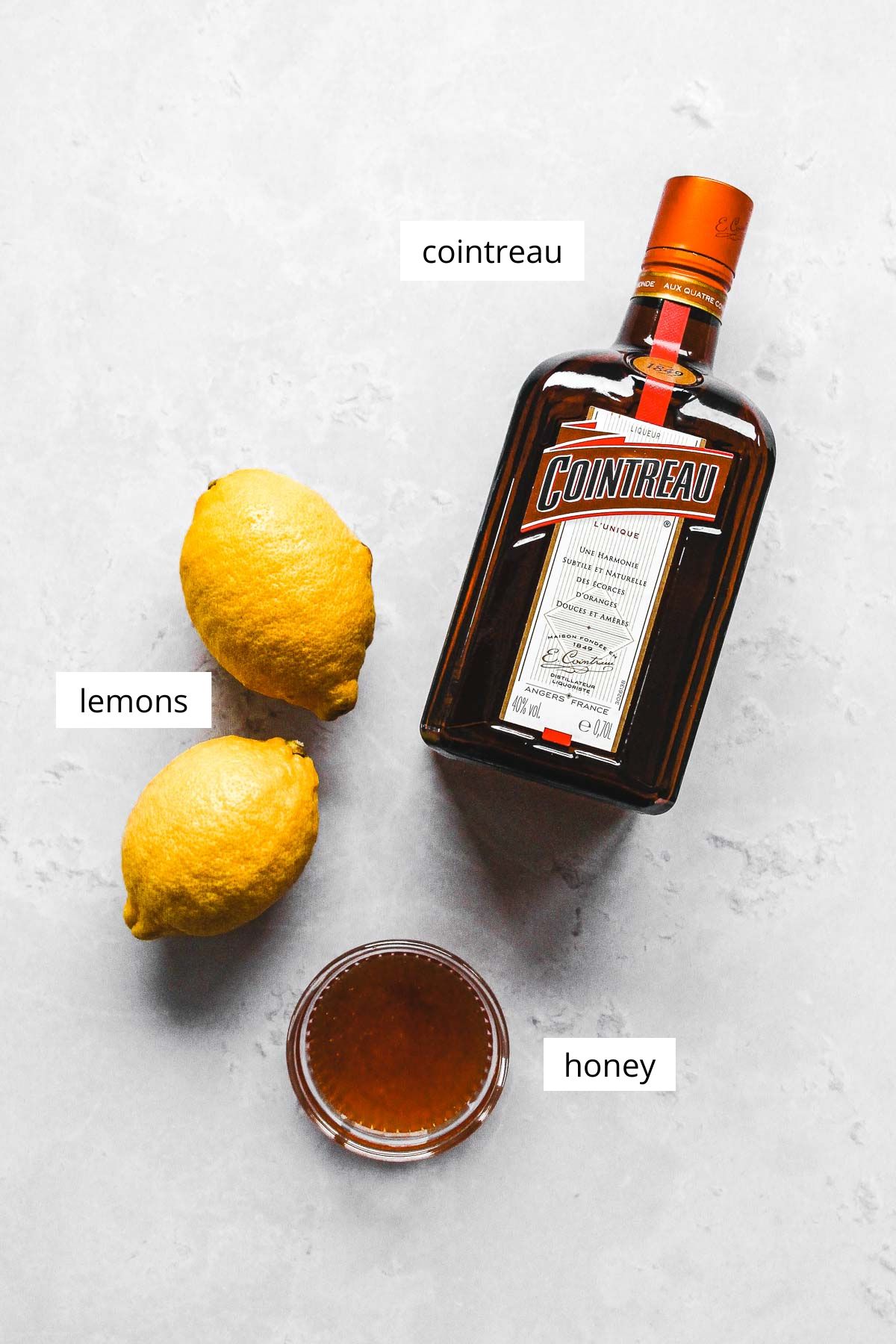 ingredients for lemon drop shots with honey on light grey background.