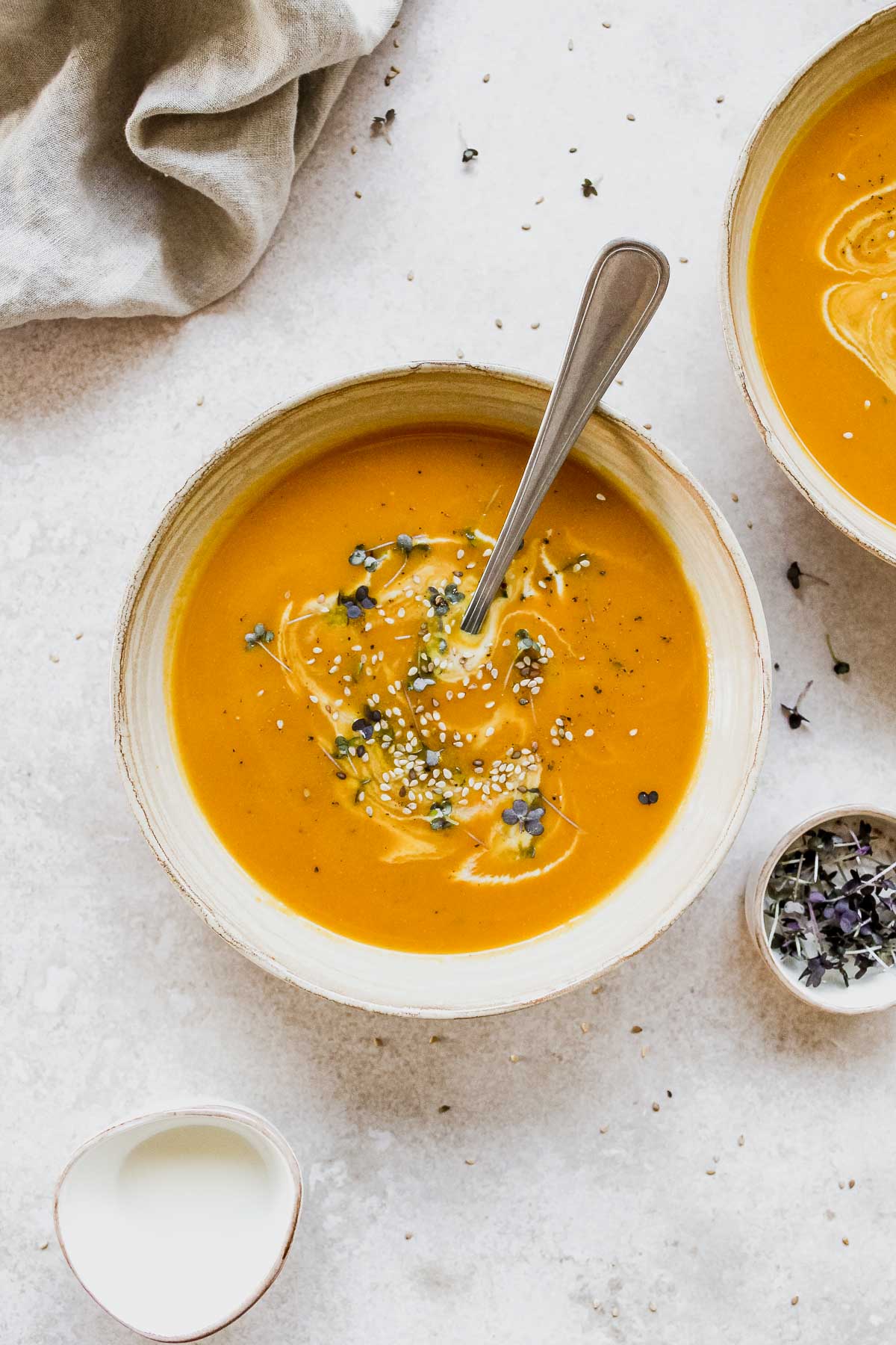 pumpkin soup in beige bowl with vintage spoon on beige background.