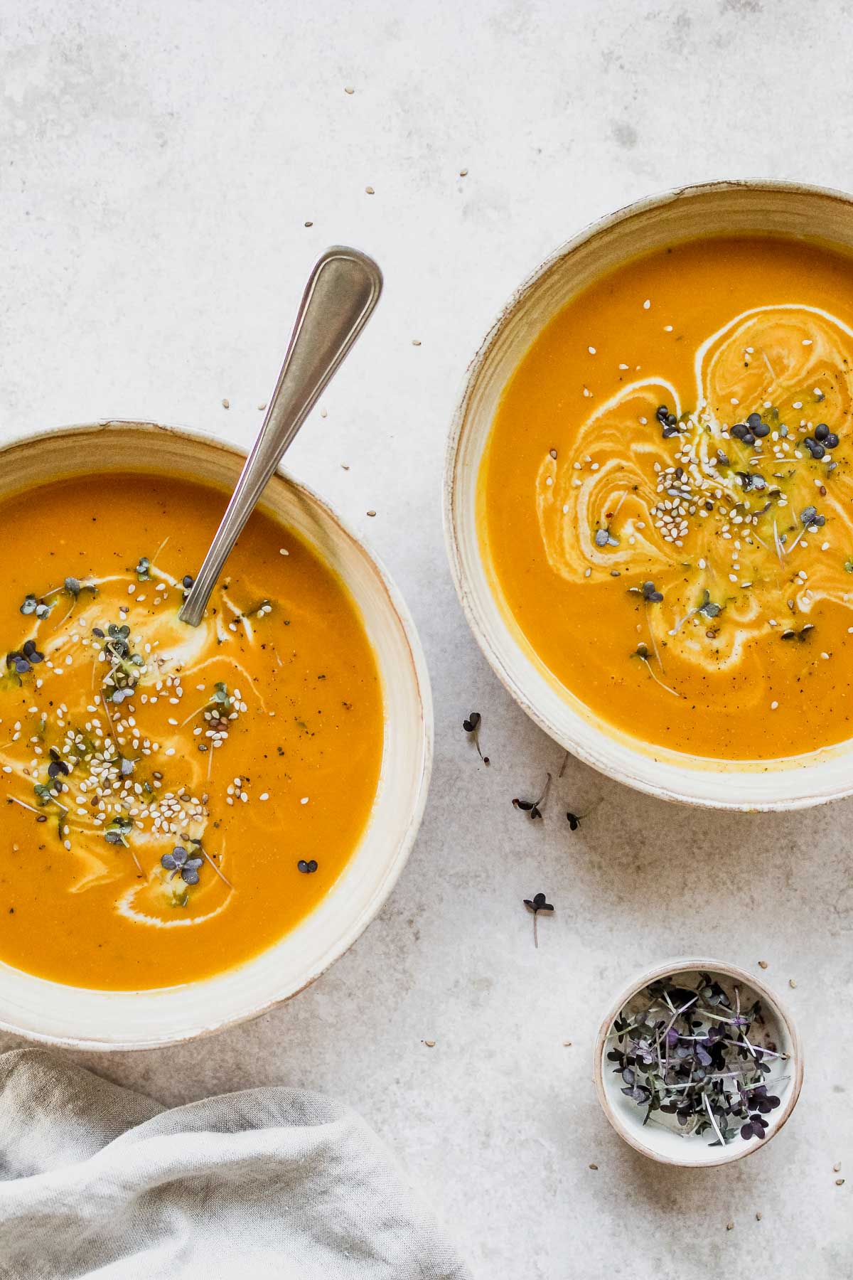 pumpkin soup in beige bowls with vintage spoon on beige background.