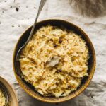 aromatic cooked sauerkraut in brown bowls with vintage spoon on beige tablecloth.