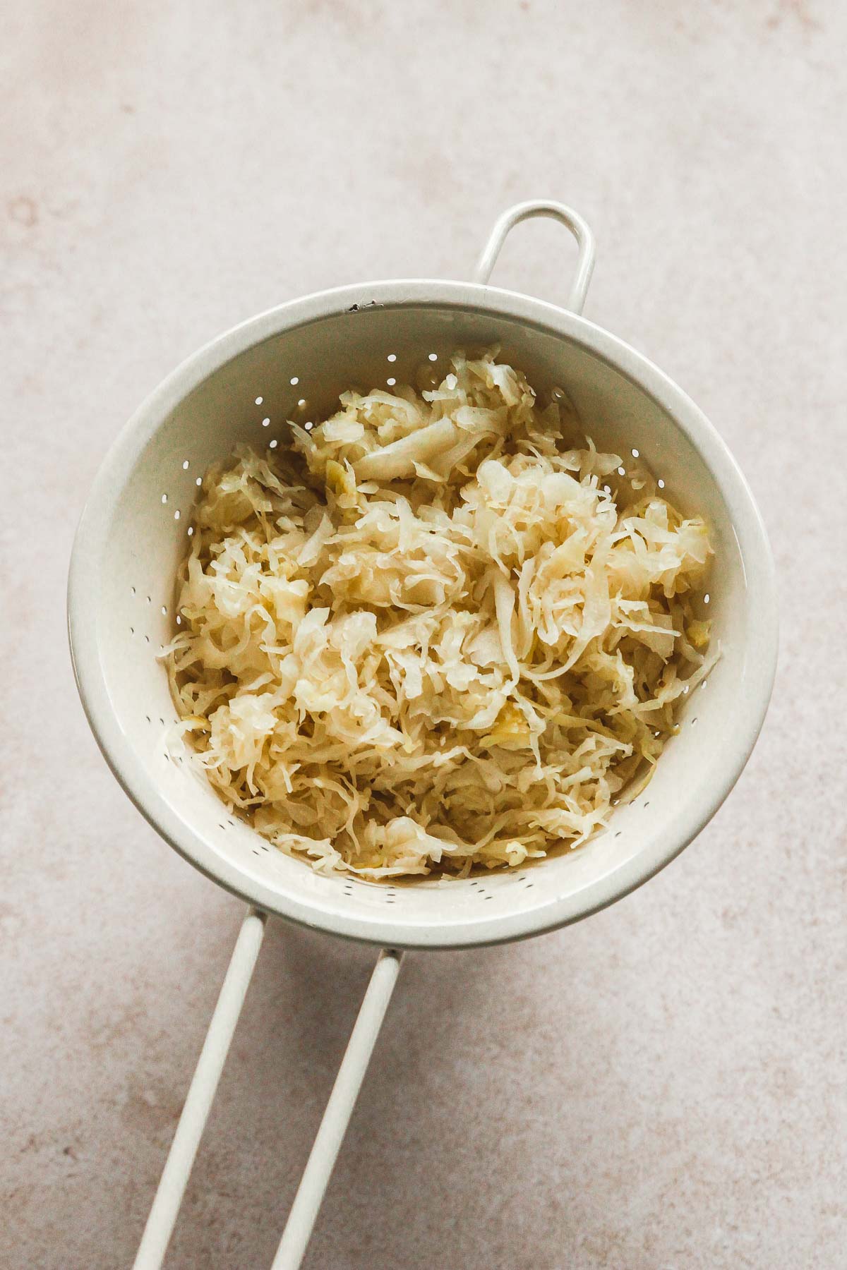 sauerkraut in colander to drain on beige background.