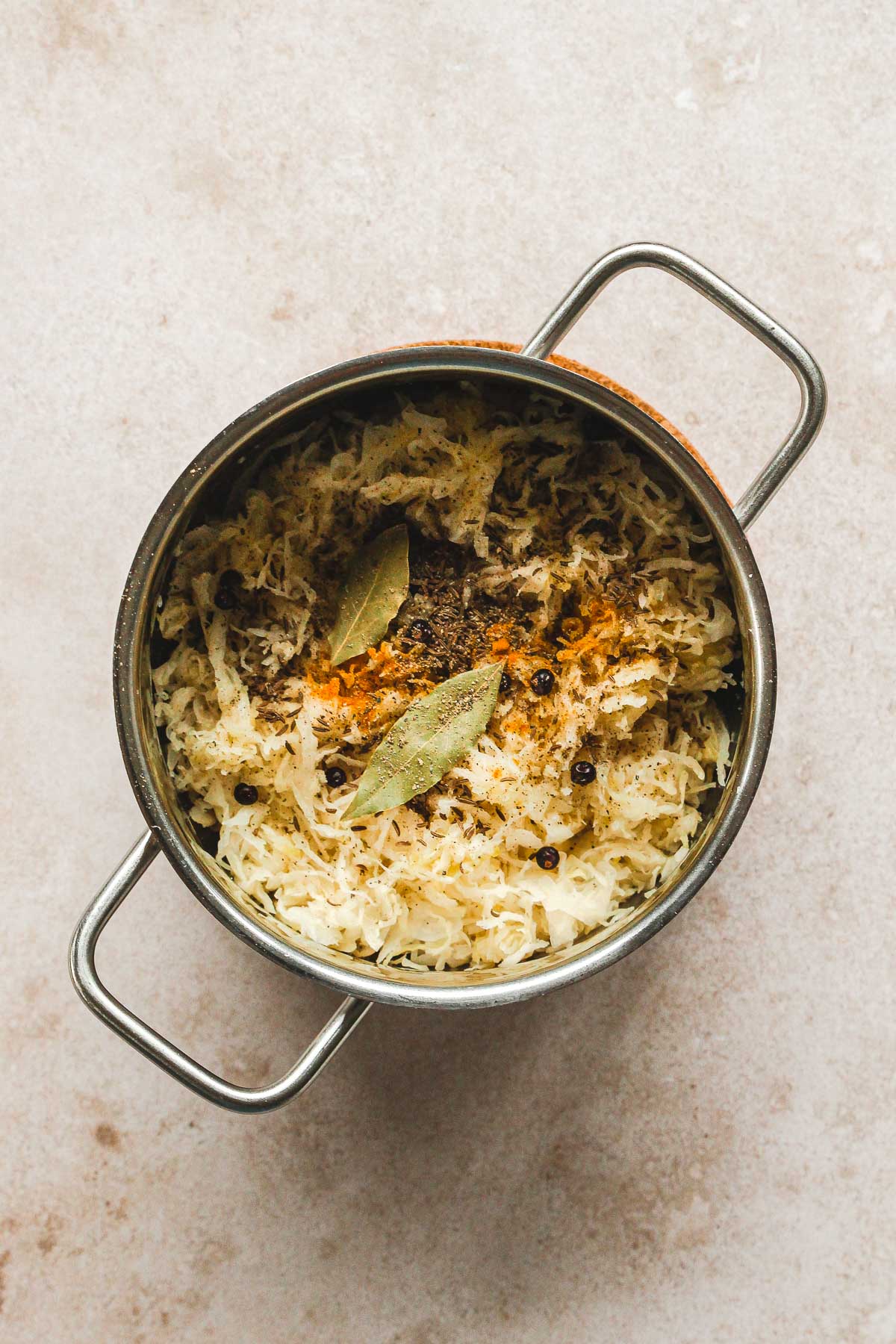 sauerkraut with spices roasting in pot on beige background.