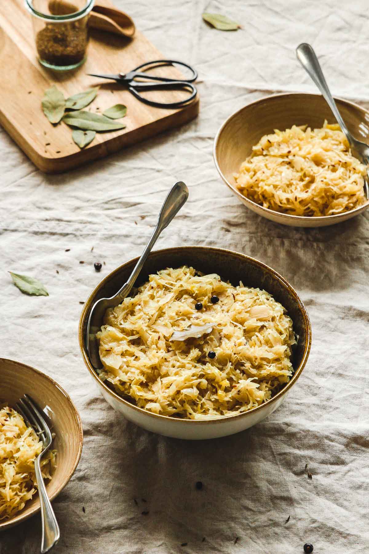 nourishing cooked sauerkraut in brown bowls with vintage spoon on beige tablecloth.