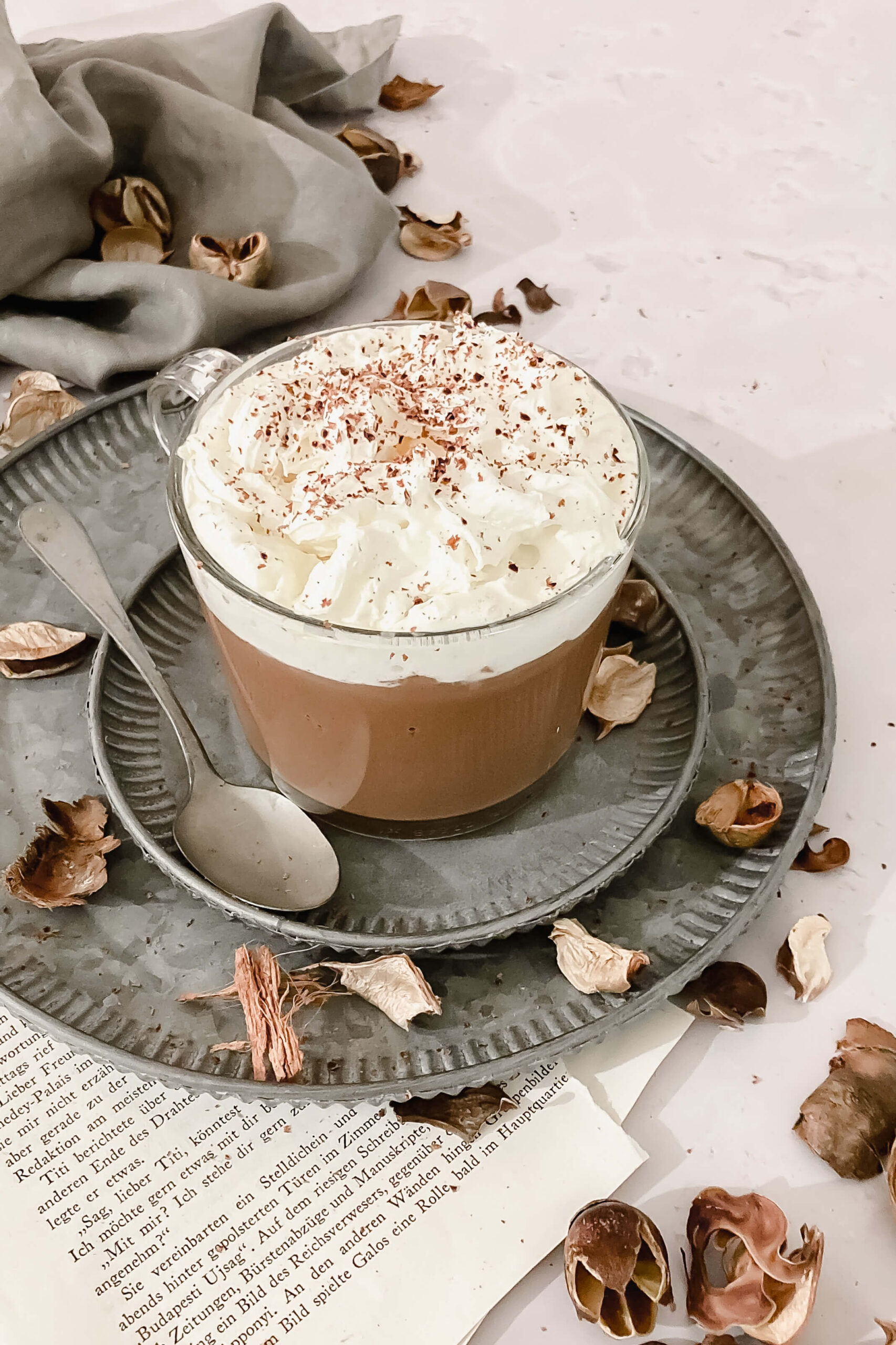 vegan hot chocolate in glass mug on with vintage spoon on vintage plates with props.