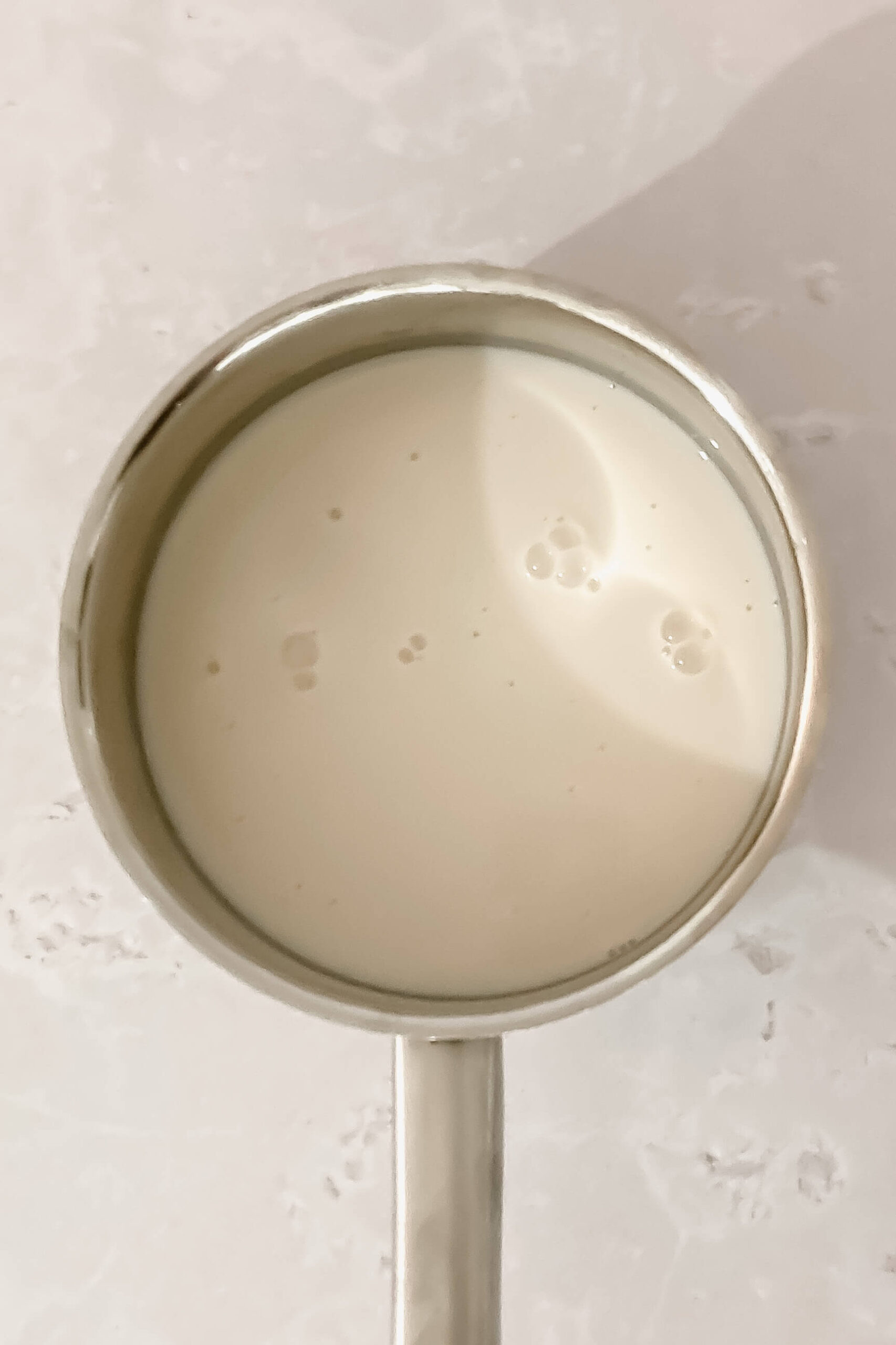 almond milk in small saucepan on beige background.