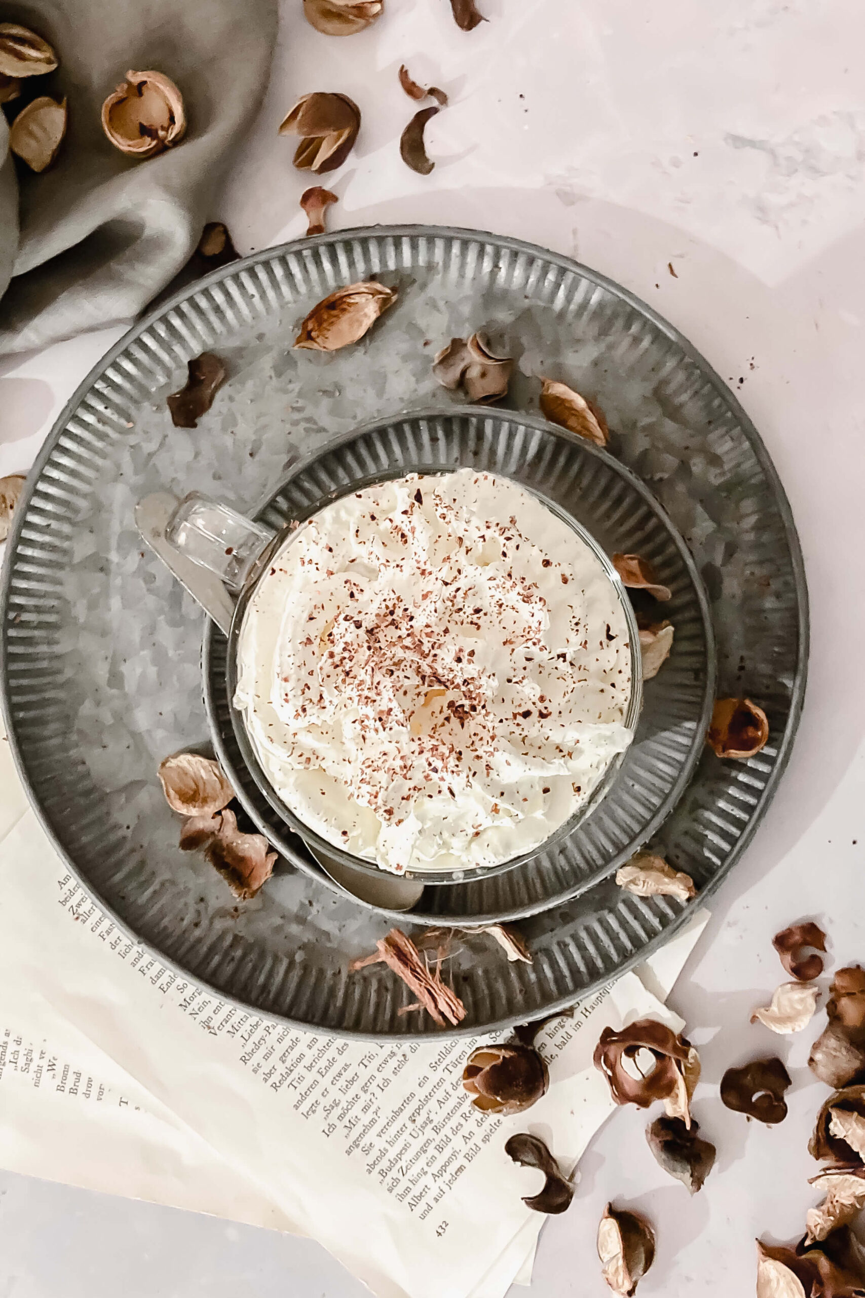 hot chocolate in glass mug on with vintage spoon on vintage plates with props.