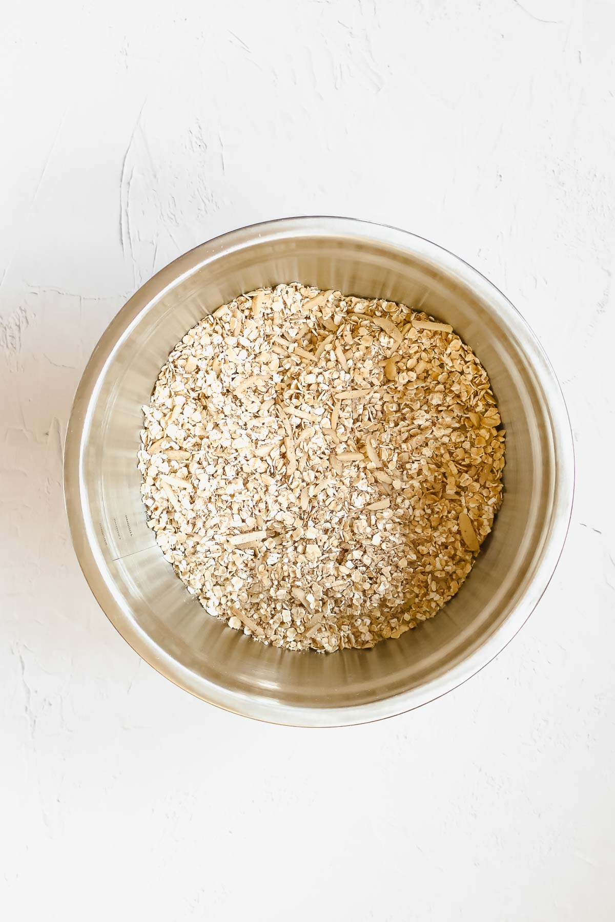 mixed dry ingredients for christmas spiced granola in metal bowl.