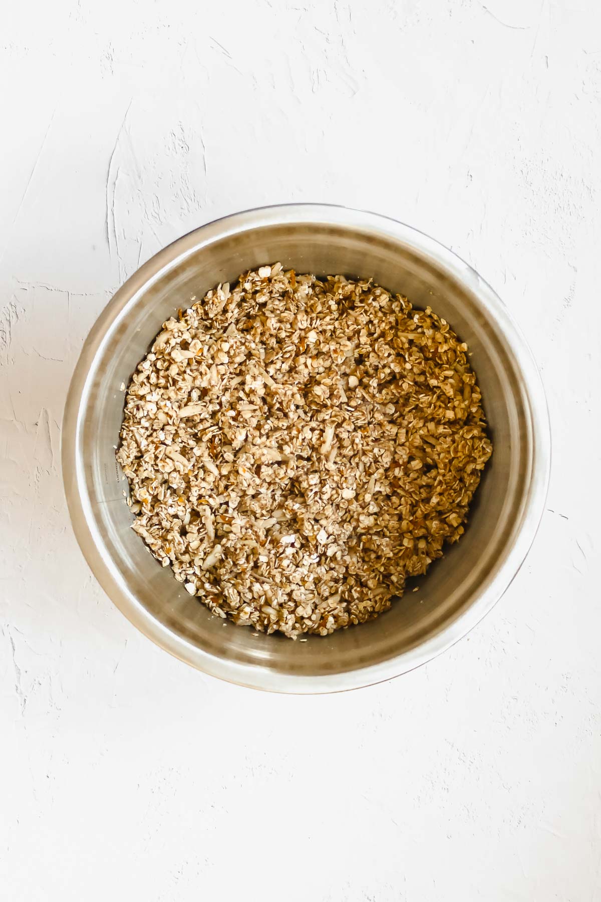 mixed ingredients for gingerbread granola in metal bowl.