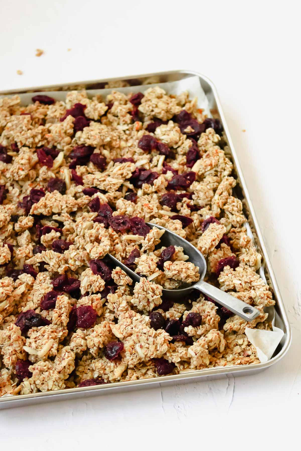 holiday spiced granola with cranberries on baking sheet with vintage serving spoon.