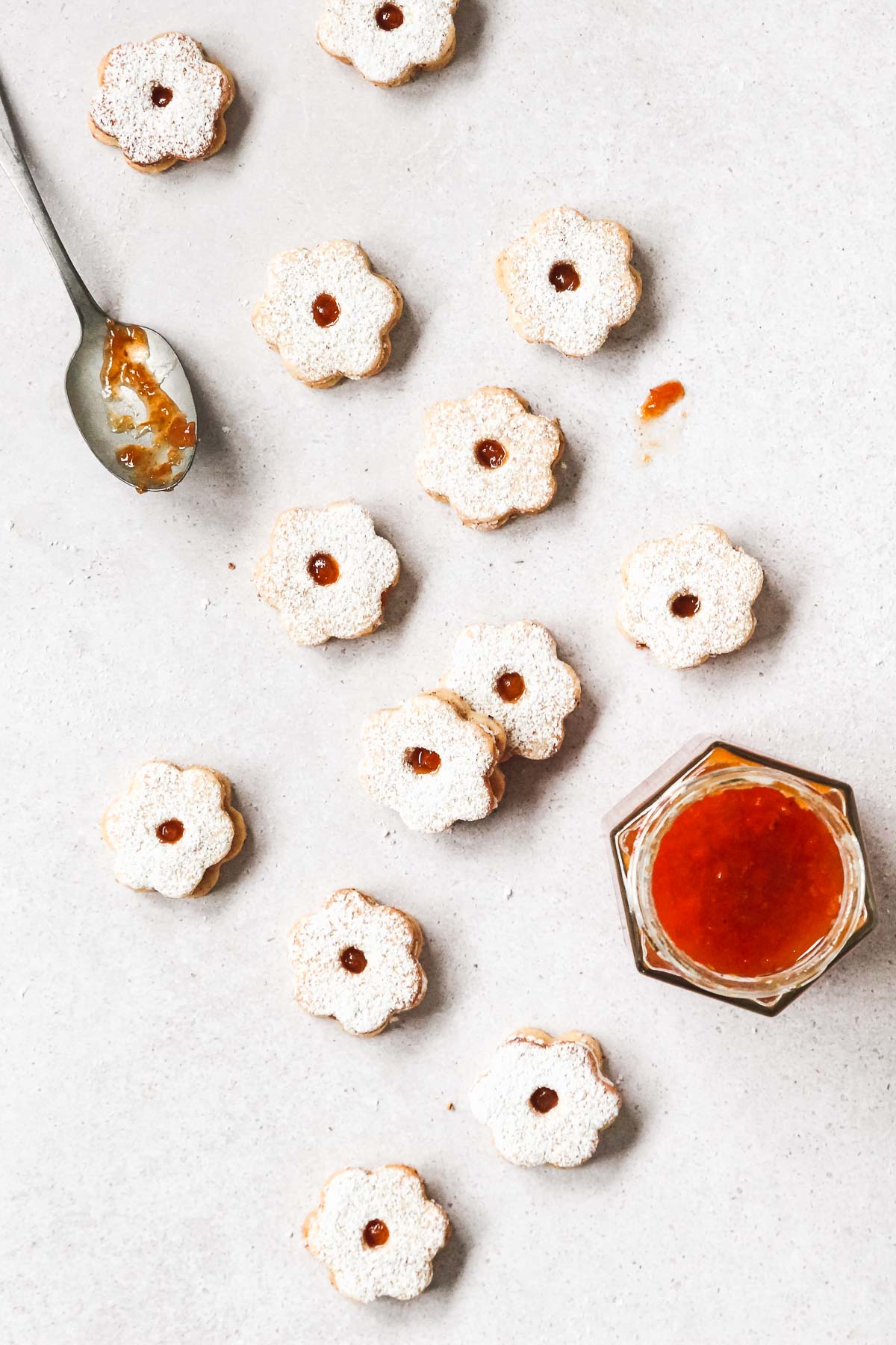 linzer cookies on grey background with vintage spoon and apricot jam.