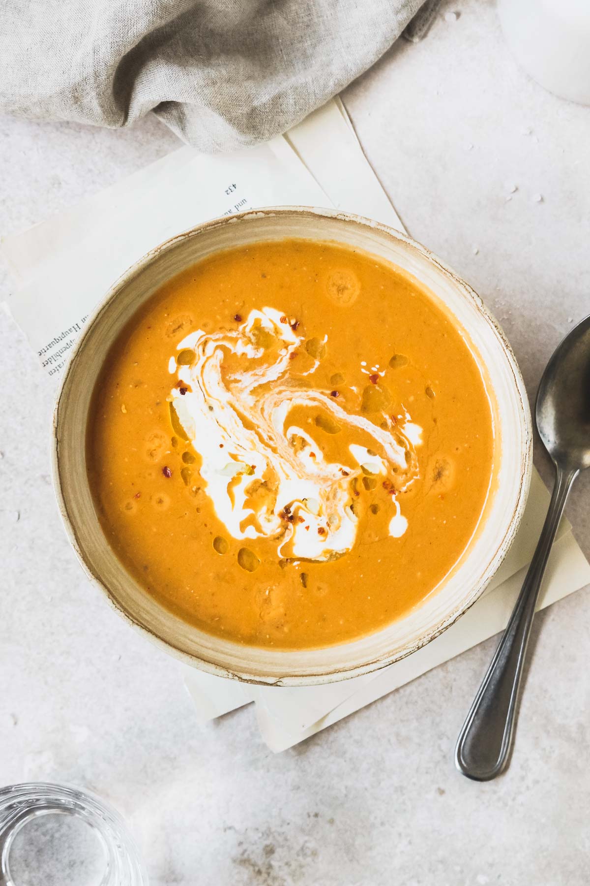 mediterranean lentil soup in beige bowl with vintage spoon on vintage grey background.