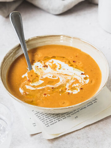 mediterranean lentil soup in beige bowl with vintage spoon on vintage grey background.