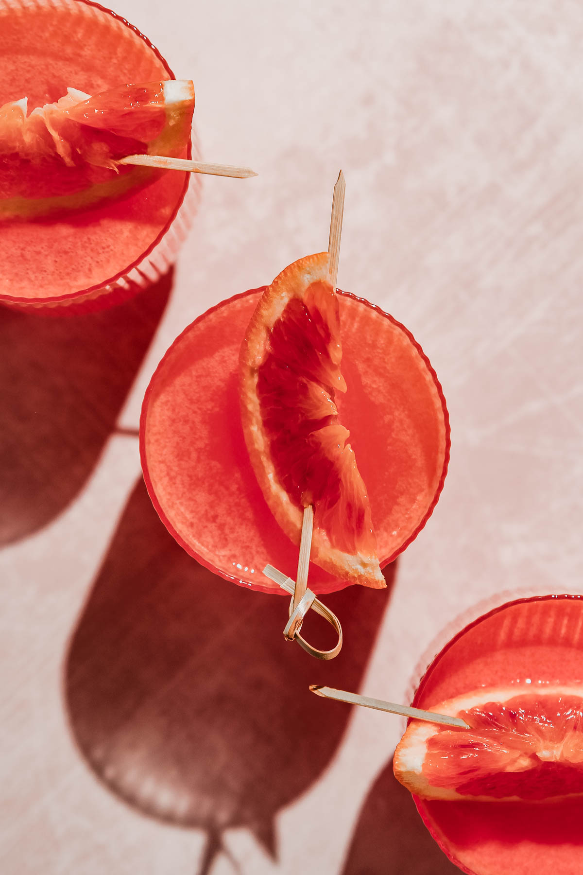 overhead shot of blood orange vodka on rosy background.