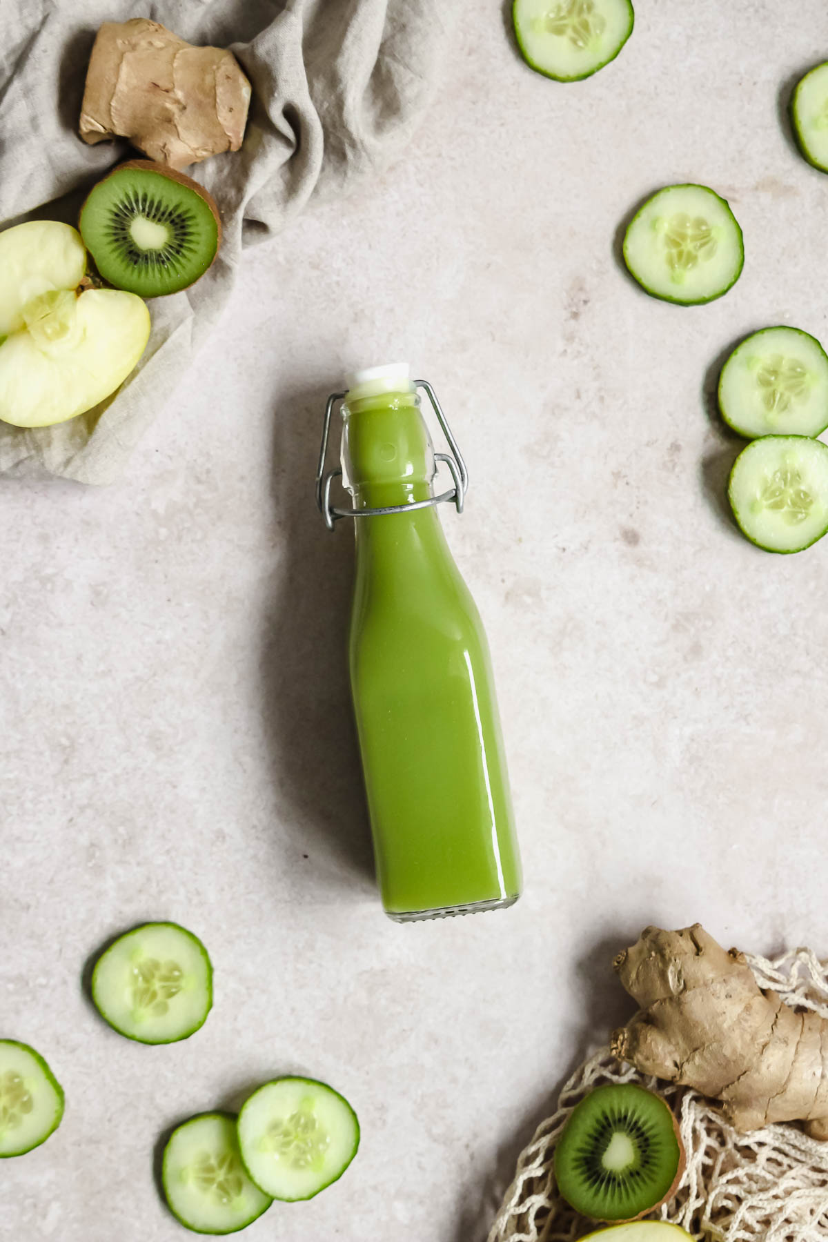 flatlay of detoxing green juice on beige background with with fruits and vegetables.