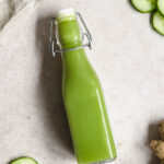 flatlay of detoxing green juice on beige background with with fruits and vegetables.