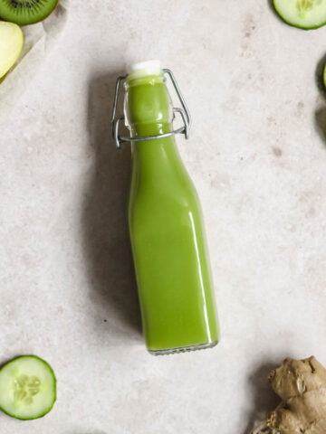 flatlay of detoxing green juice on beige background with with fruits and vegetables.