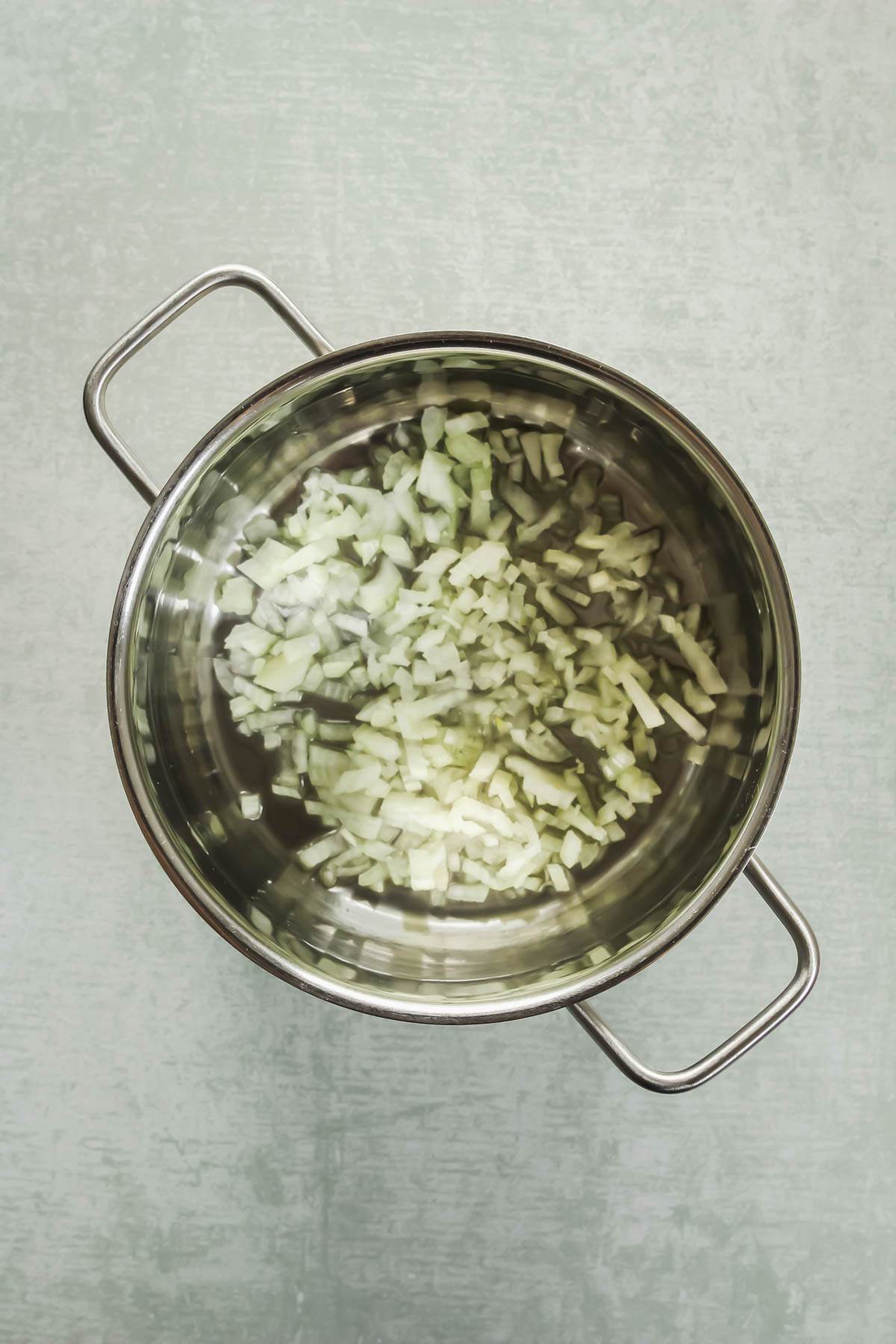 roasting chopped onions in pot on green background.