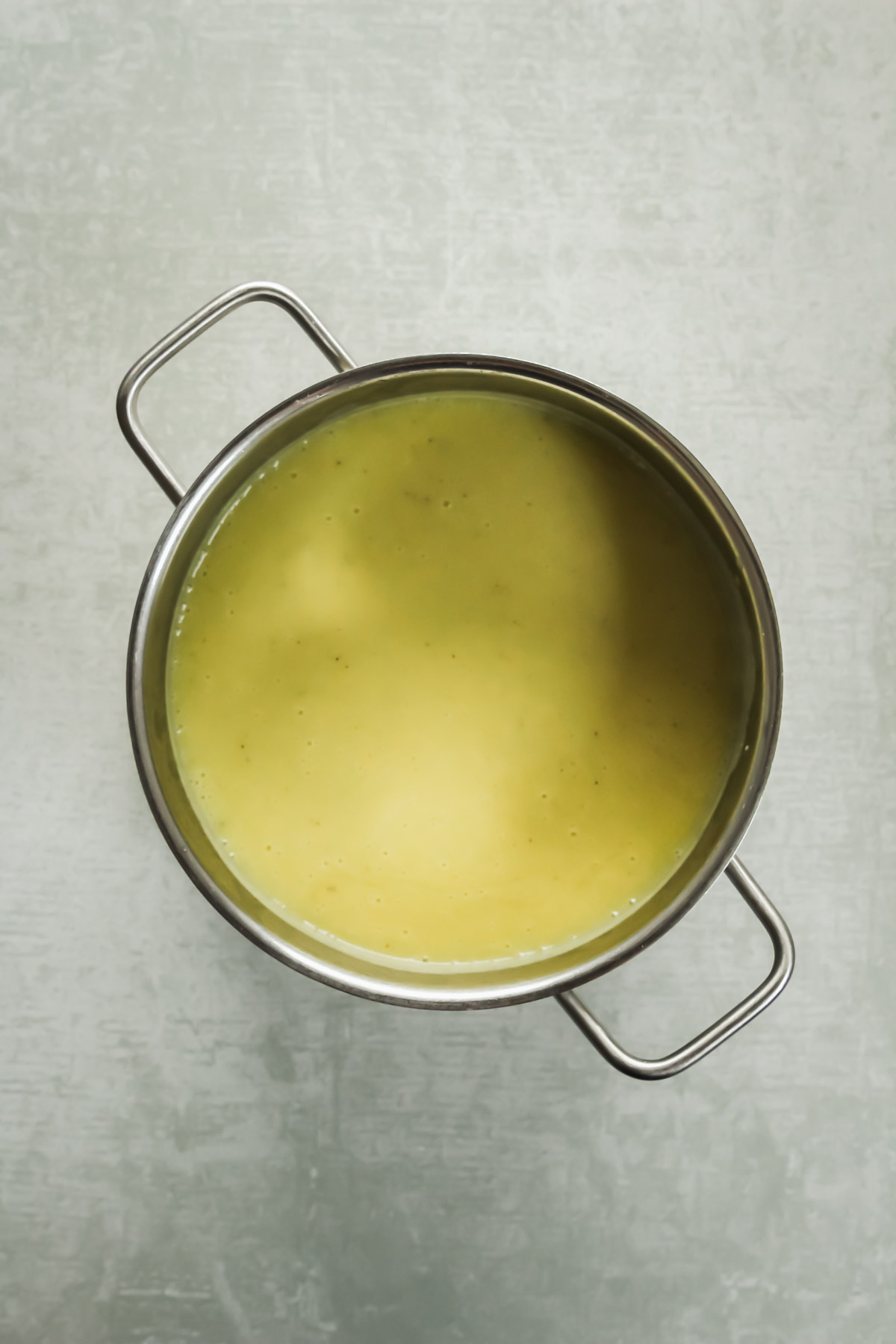 creamy low carb vegan soup in pot on green background.